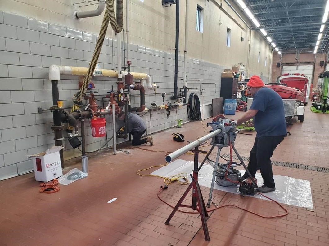 A man is working on a pipe in a factory.