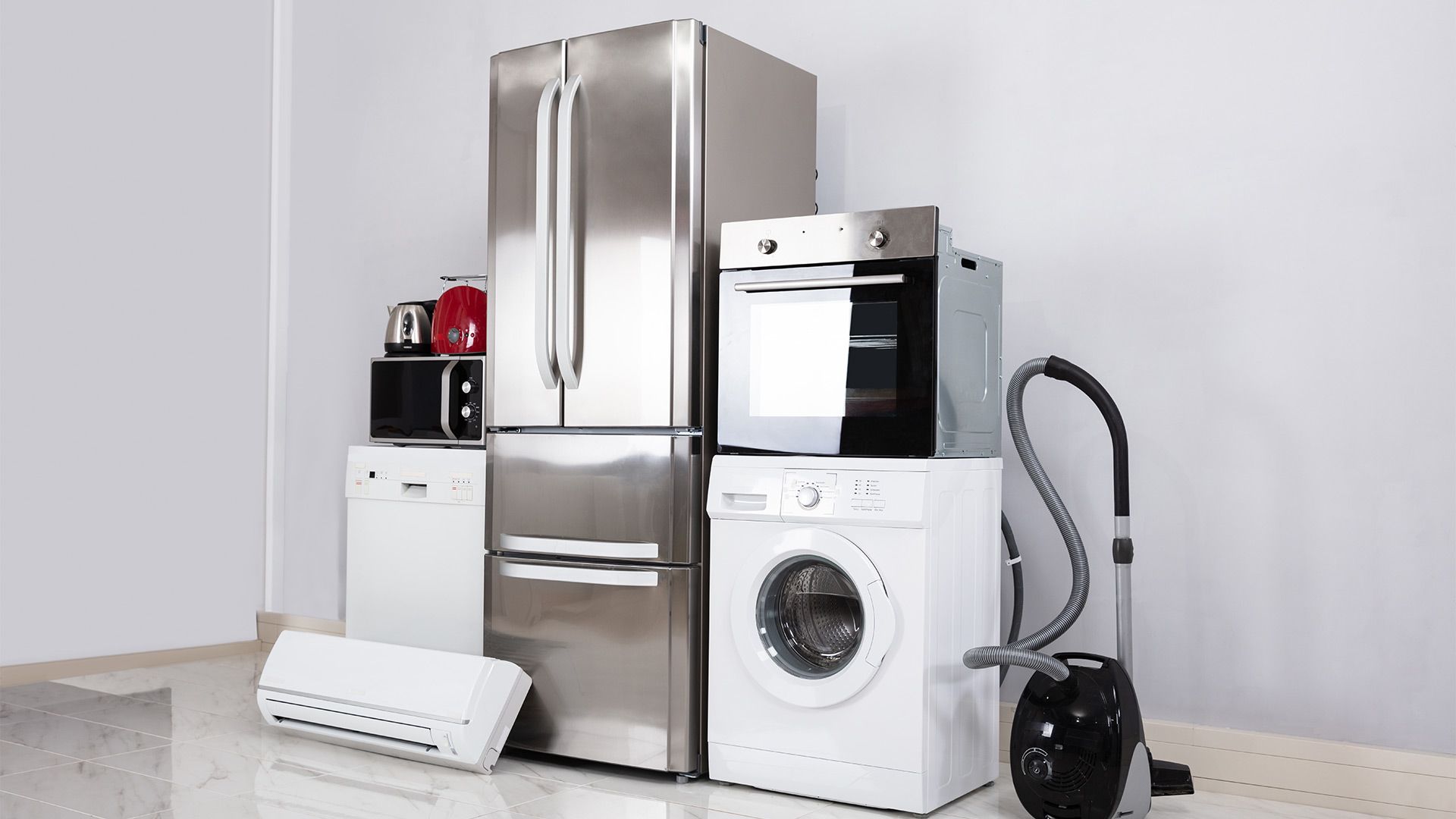 A refrigerator , washing machine , oven , microwave , air conditioner and vacuum cleaner are in a room.