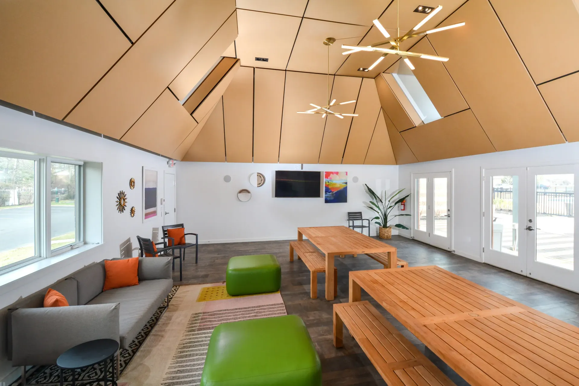 Interior community lounge with a sloped wooden ceiling, tables, and seating.