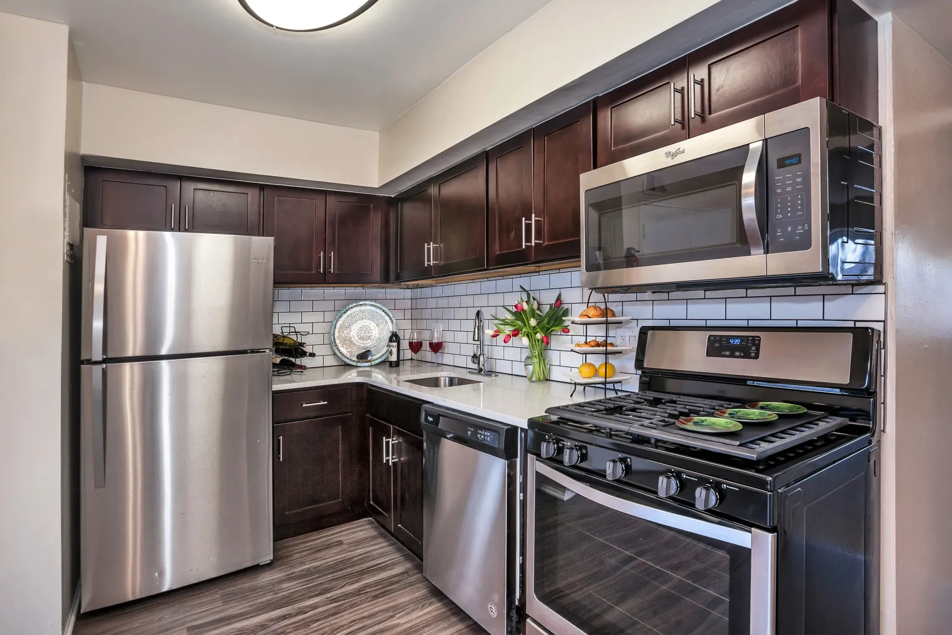 Modern kitchen with dark wood cabinets and stainless steel appliances; white subway tile backsplash.