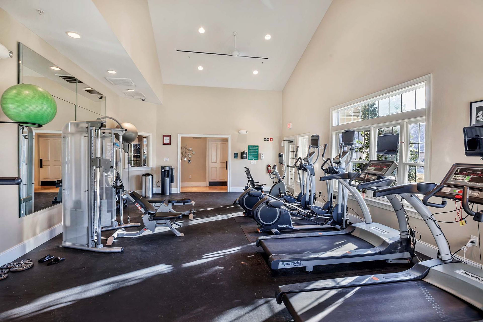 Bright fitness center with treadmills, ellipticals, and weight machines.