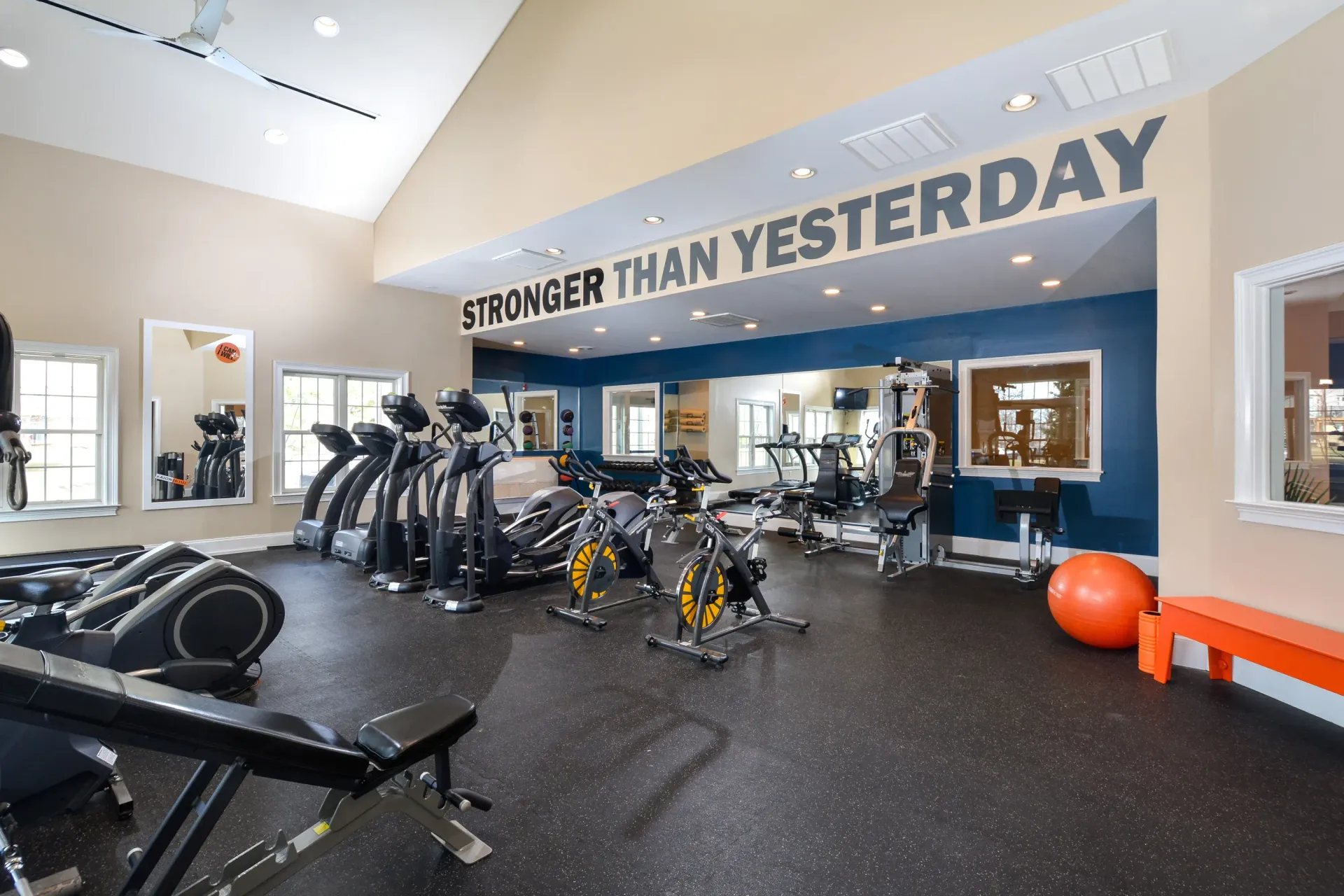 Bright, modern apartment gym with cardio machines and mirrors.