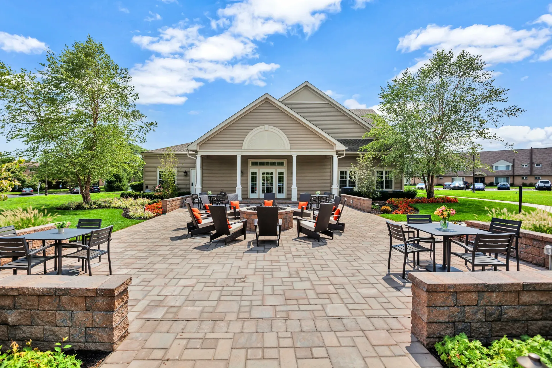 Brick-paved communal courtyard with outdoor seating and a central fire pit near the building entrance.