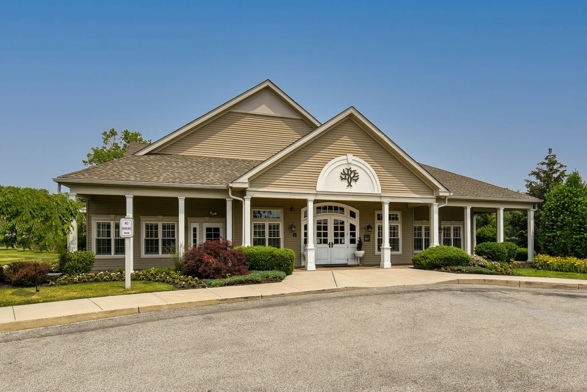 Exterior view of a beige apartment community clubhouse with white columns and a covered entrance.