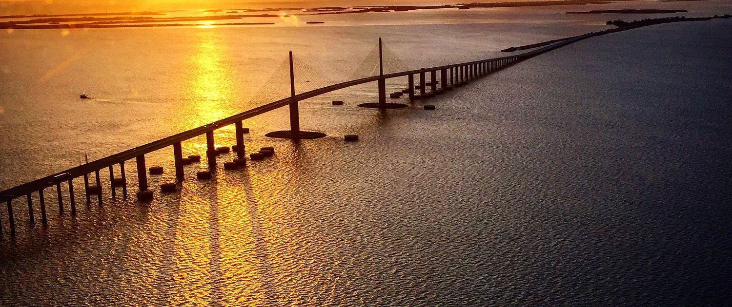 A Bridge Over A Body Of Water At Sunset — St. Petersburg, FL — Executive Helicopter Tours