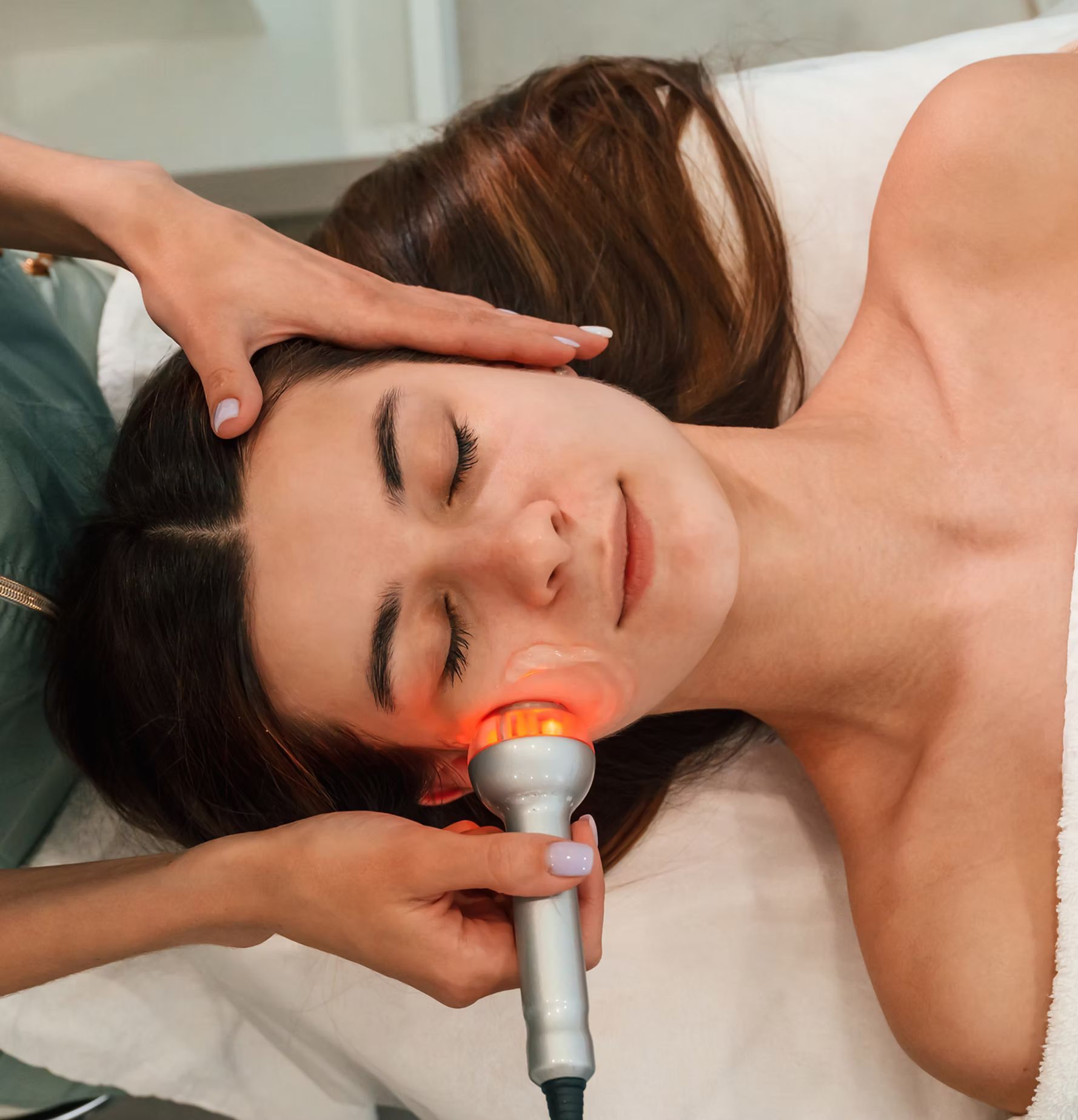 A woman is laying on a bed getting a facial treatment.