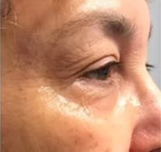 A close up of a woman 's face with a tear coming out of her eye.