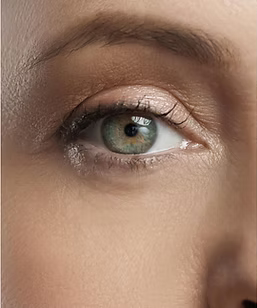 A close up of a woman 's green eye with makeup on.