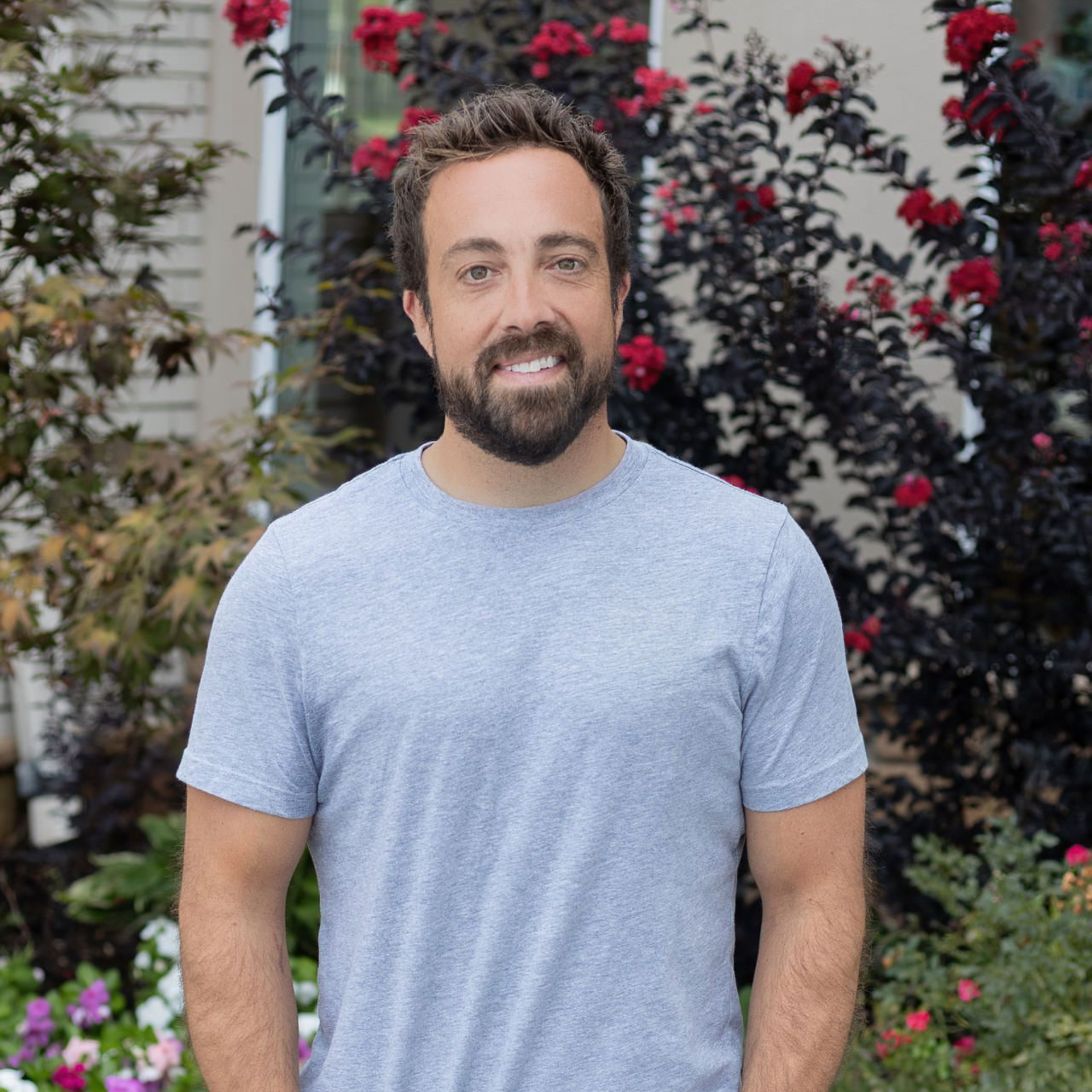 A man with a beard is standing in a room with his hands in his pockets.