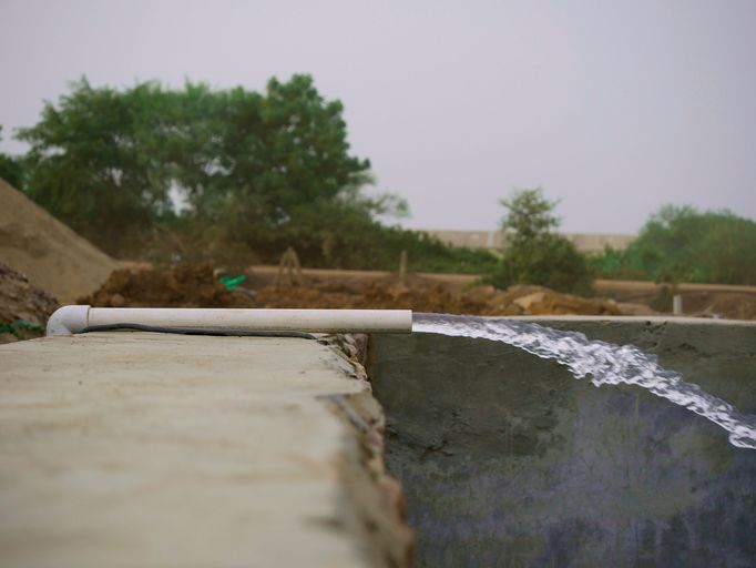 Water force flowing with pressure on cement tank at natural background