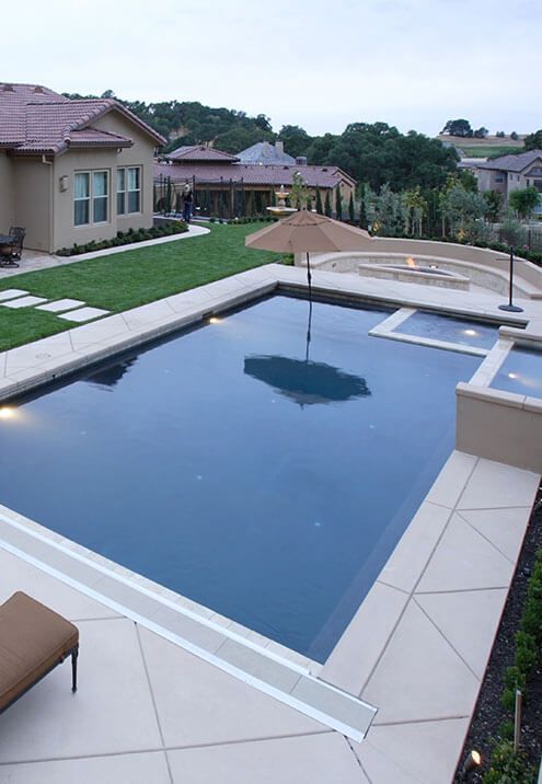 A large swimming pool with a house in the background