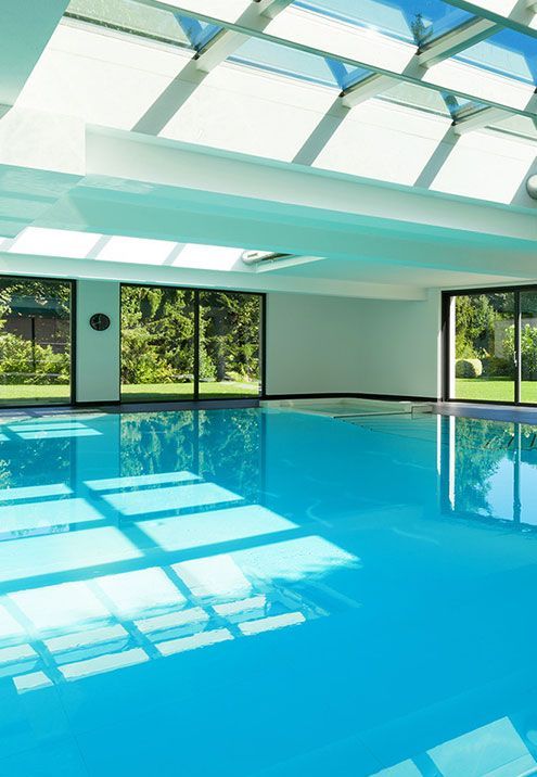 A large indoor swimming pool with a glass roof