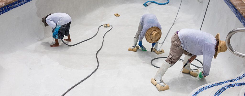 Three men are working on a swimming pool.