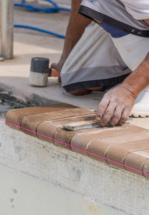 A man is kneeling down while working on a swimming pool.