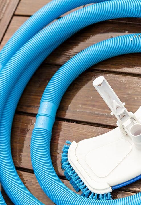 A blue hose and brush are sitting on a wooden deck.