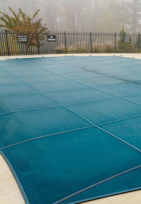 A blue pool cover is sitting on top of a swimming pool.