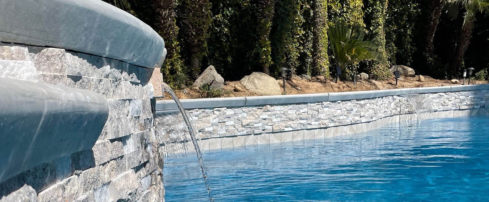 There is a waterfall in the middle of a swimming pool.