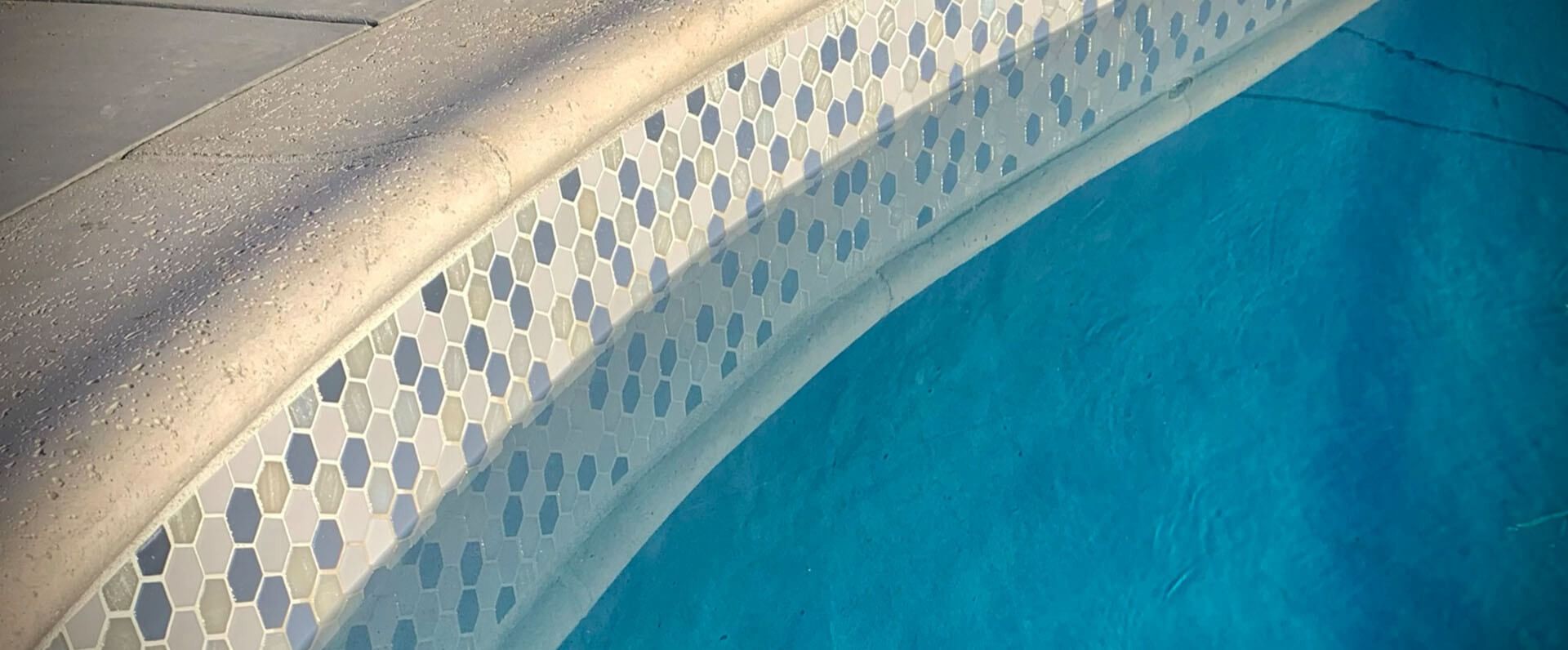 A swimming pool with blue water and white tiles on the edge.