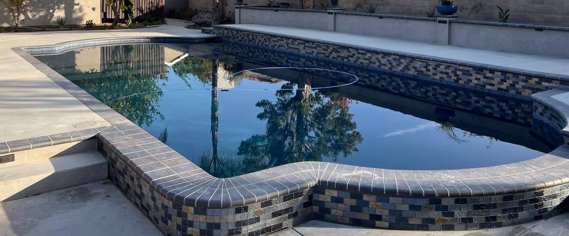 A large swimming pool with a reflection of palm trees in the water.