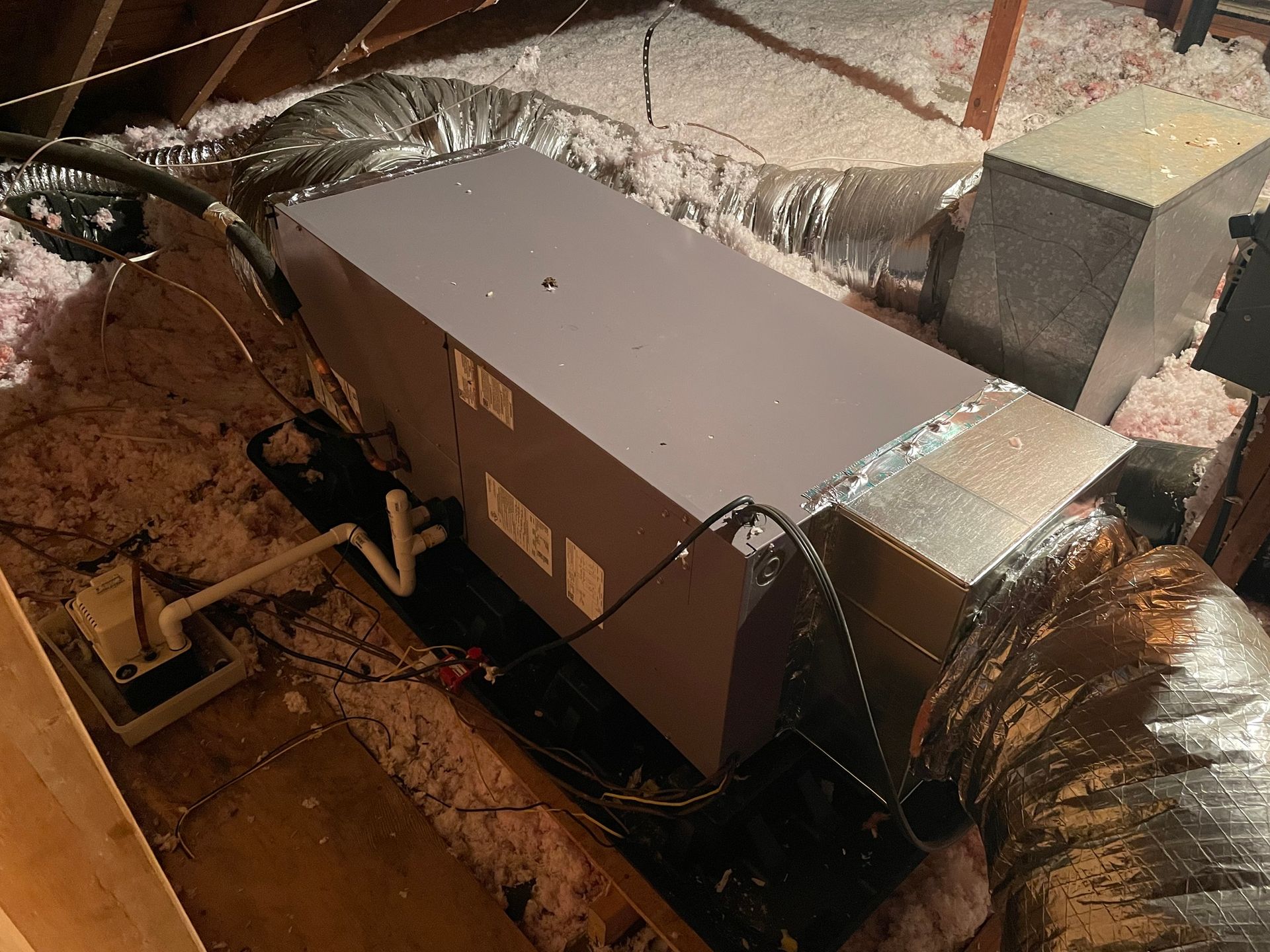 An air conditioner is sitting in the attic of a house.