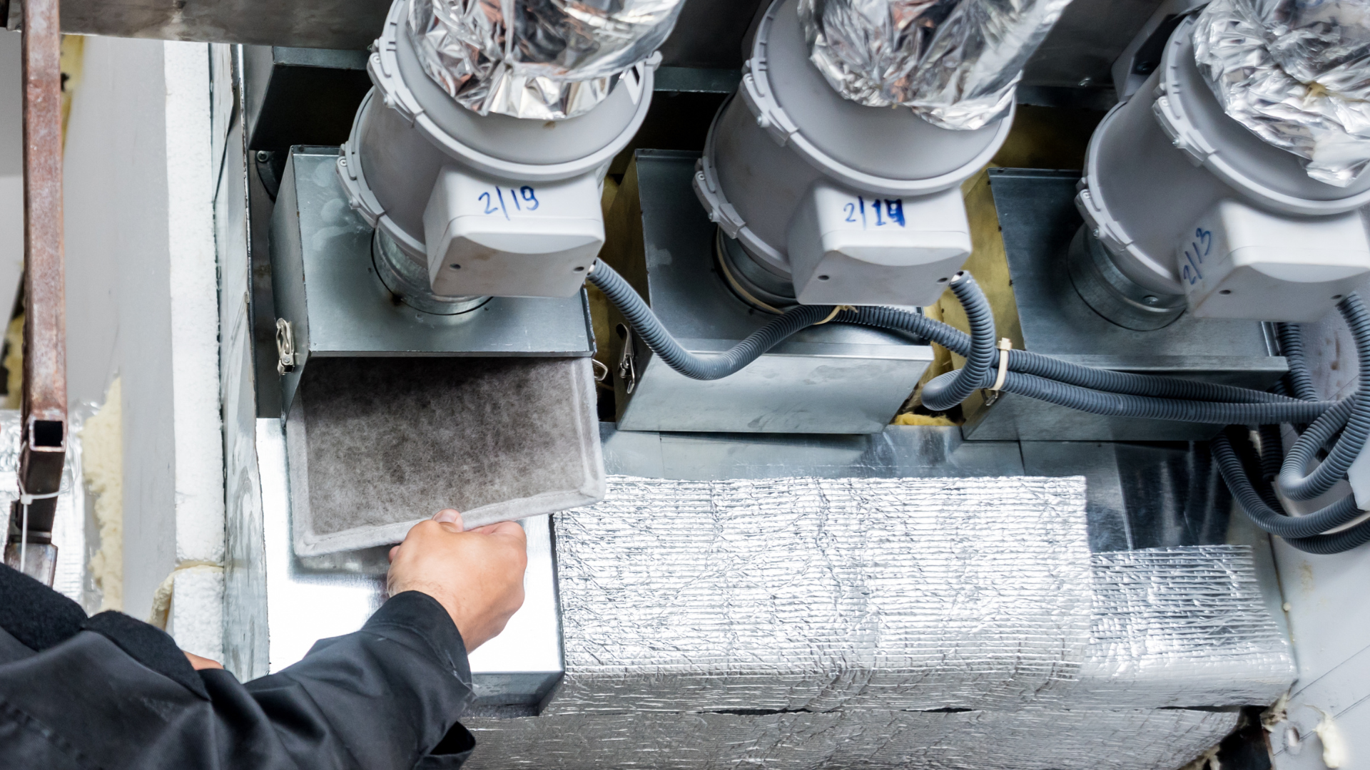 A man is working on a ventilation system in a building.