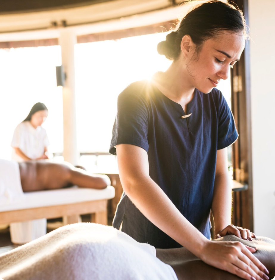 A woman in a blue shirt is giving a man a massage