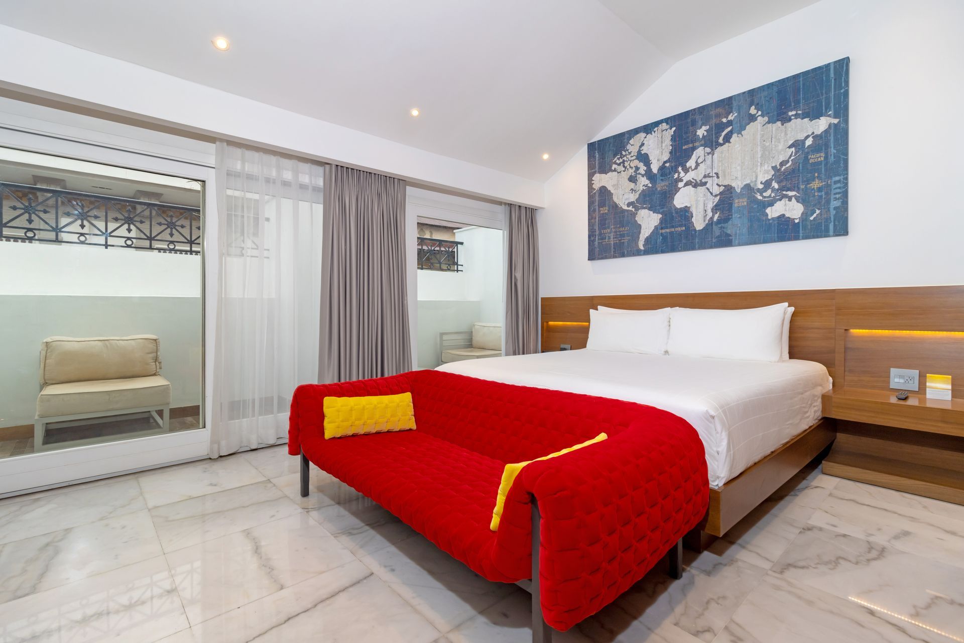 Dormitorio con un sofá rojo, un mapa en la pared y una cama con sábanas blancas.