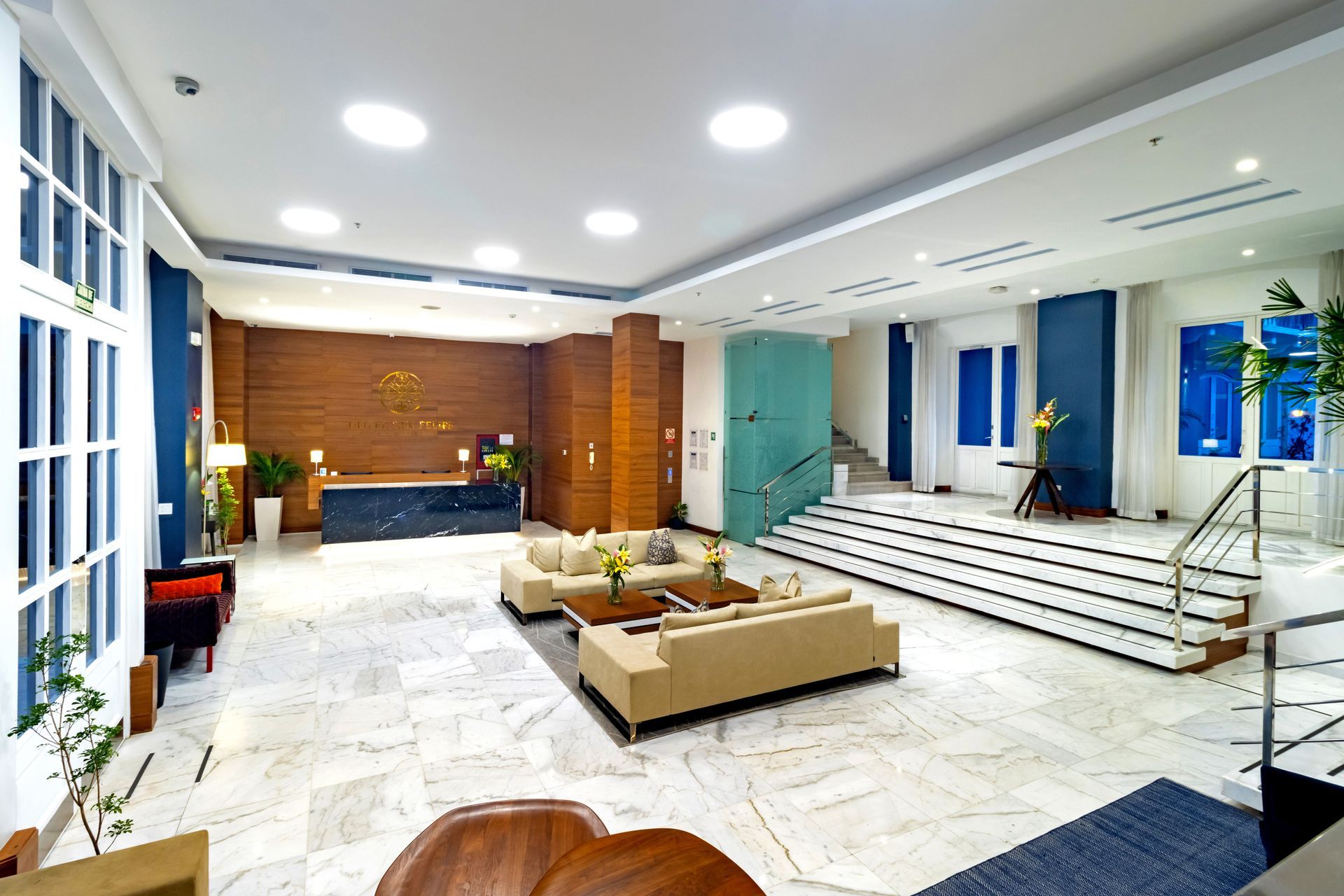 Vestíbulo del hotel con suelos de mármol, asientos y mostrador de recepción.