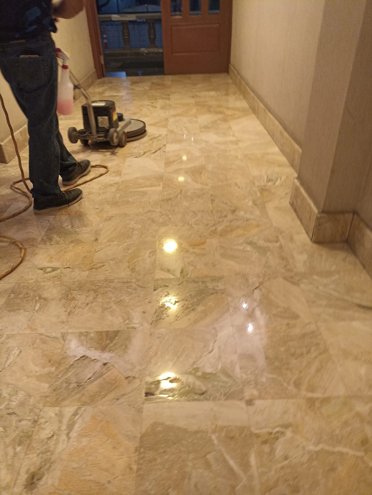 Persona puliendo un suelo de mármol beige con una máquina.