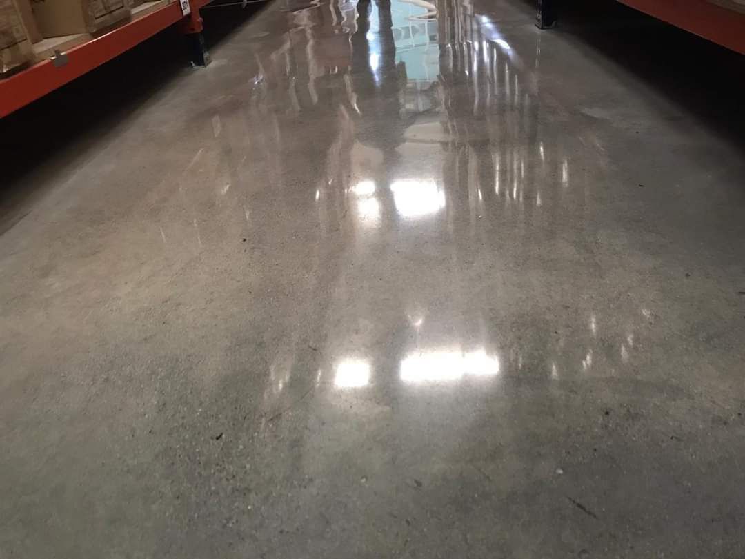 Piso de hormigón pulido que refleja la luz en el pasillo de un almacén.