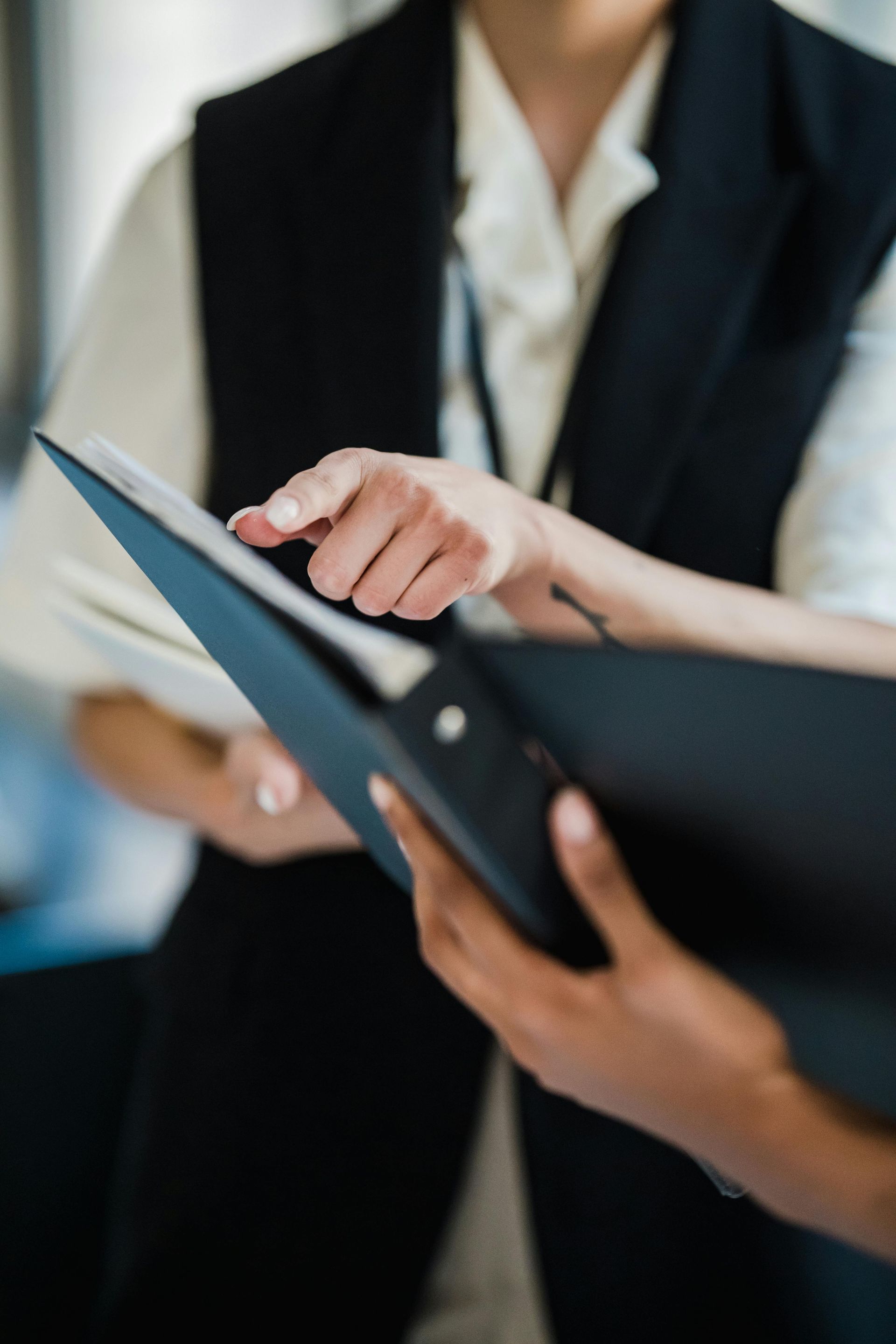 Hands pointing at a black folder during a business meeting