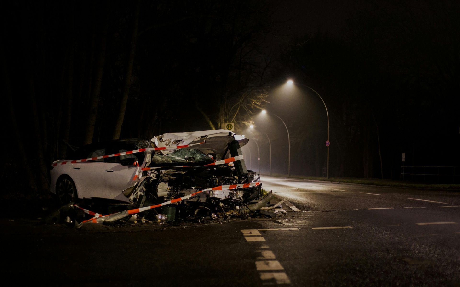 Car wreck on a dark road under streetlights, with one car badly damaged and debris scattered nearby