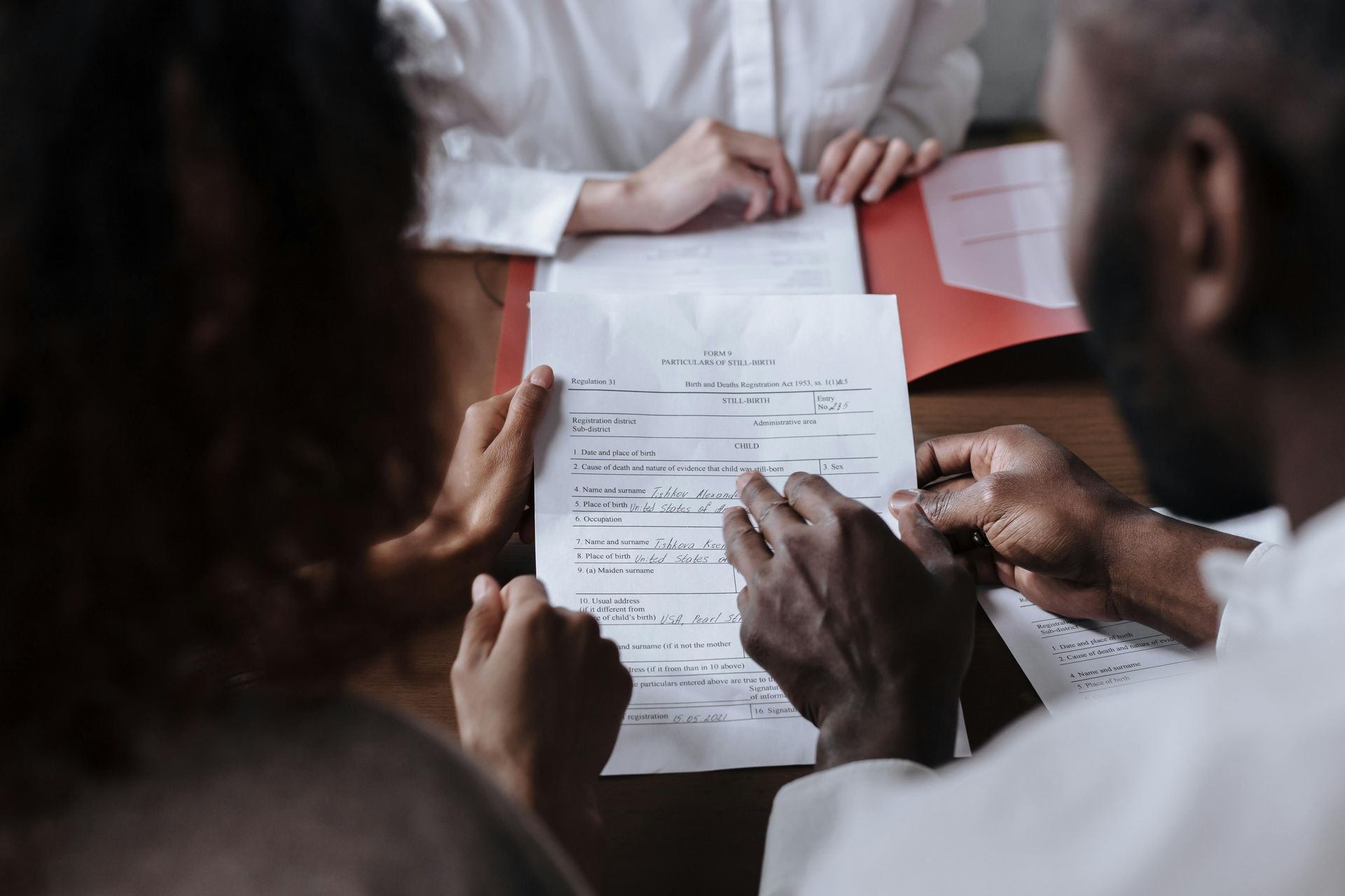 People reviewing a document at a table, with hands pointing at the paper during a discussion