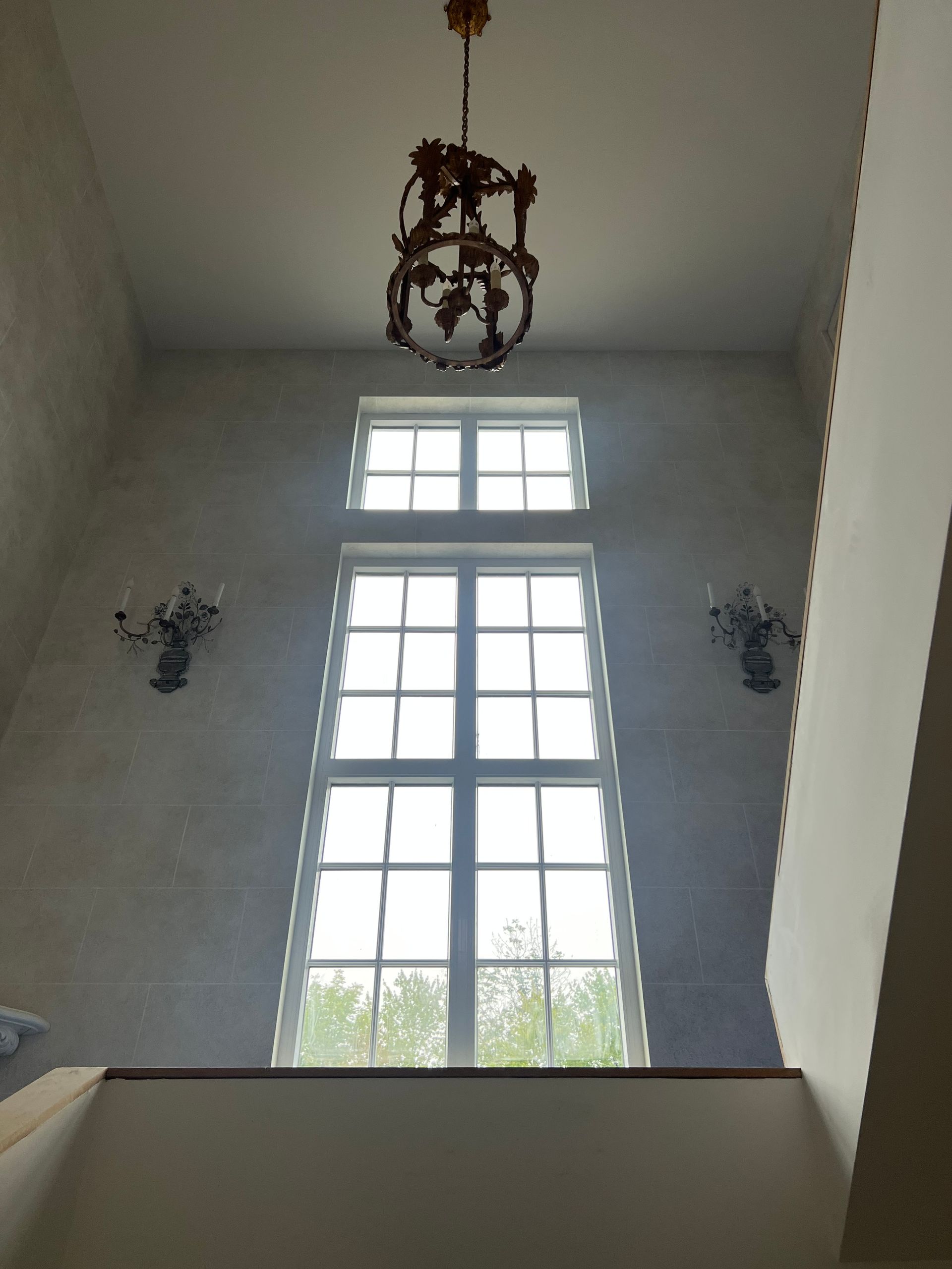 Looking up at a large window with a chandelier hanging from the ceiling