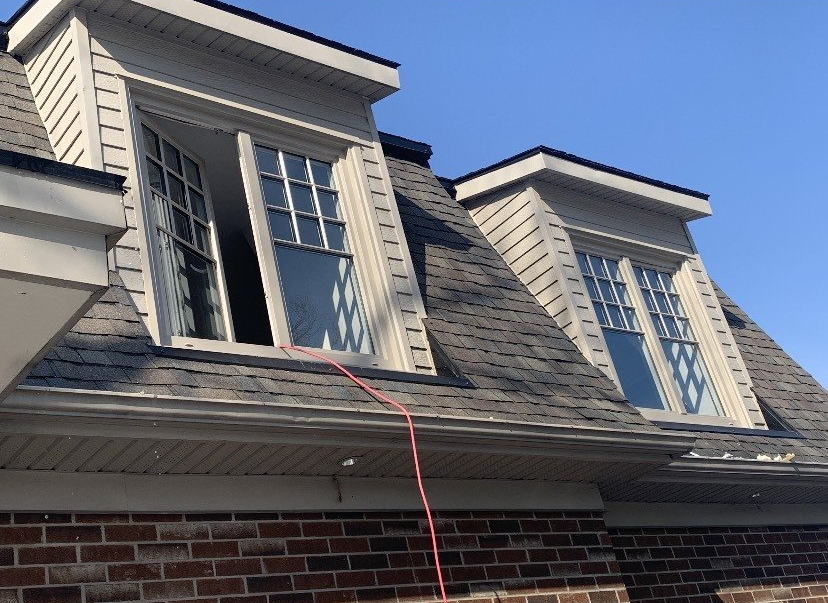 A house with two windows on the roof and a hose attached to it.