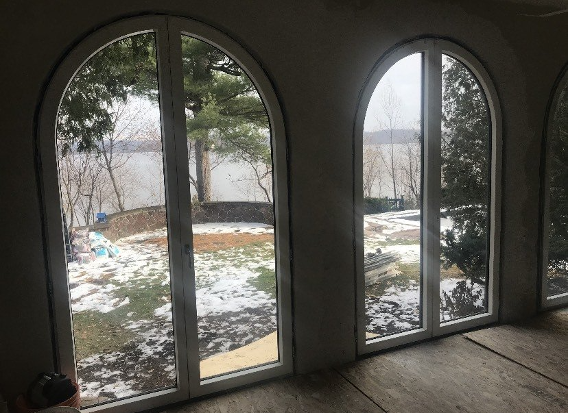 A room with arched windows and a view of a lake.