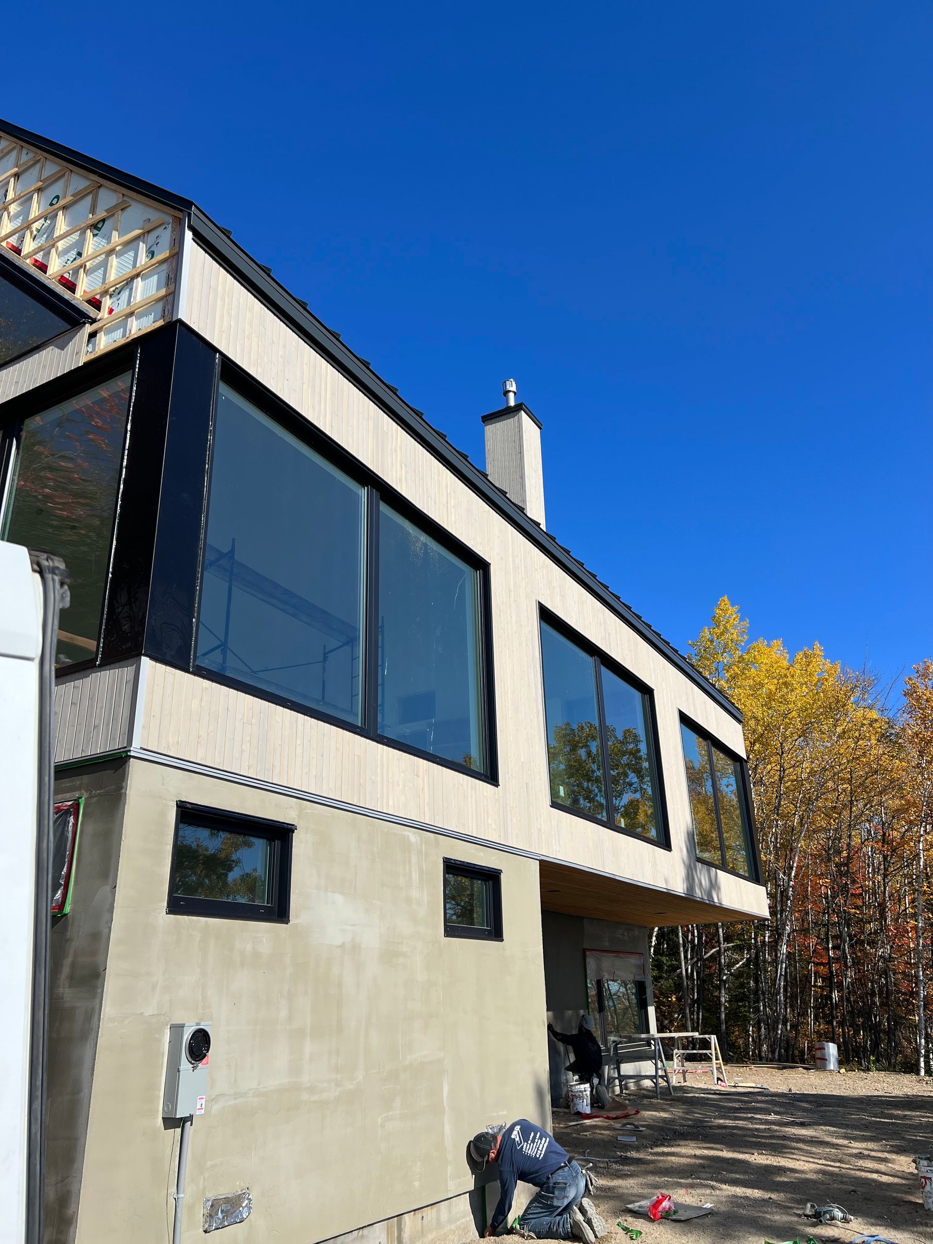 A man is kneeling in front of a large house with a lot of windows.