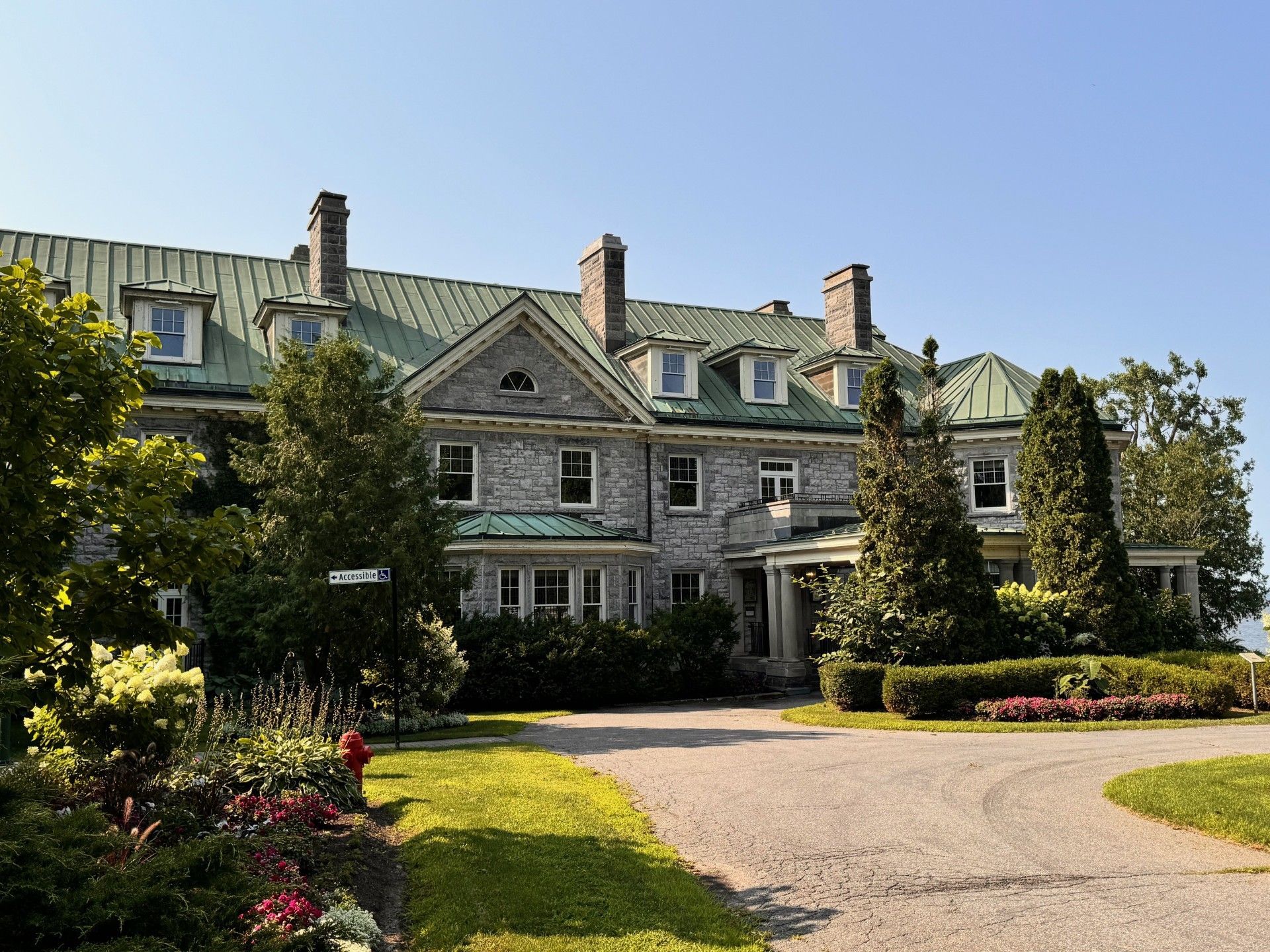 A large house with a green roof is surrounded by trees and bushes