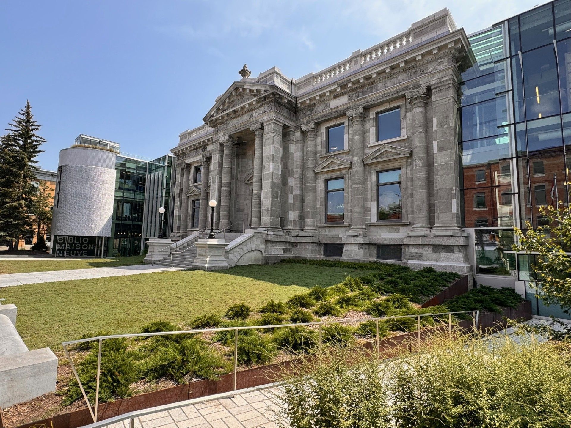 A large building with a lot of windows is surrounded by a lush green field.