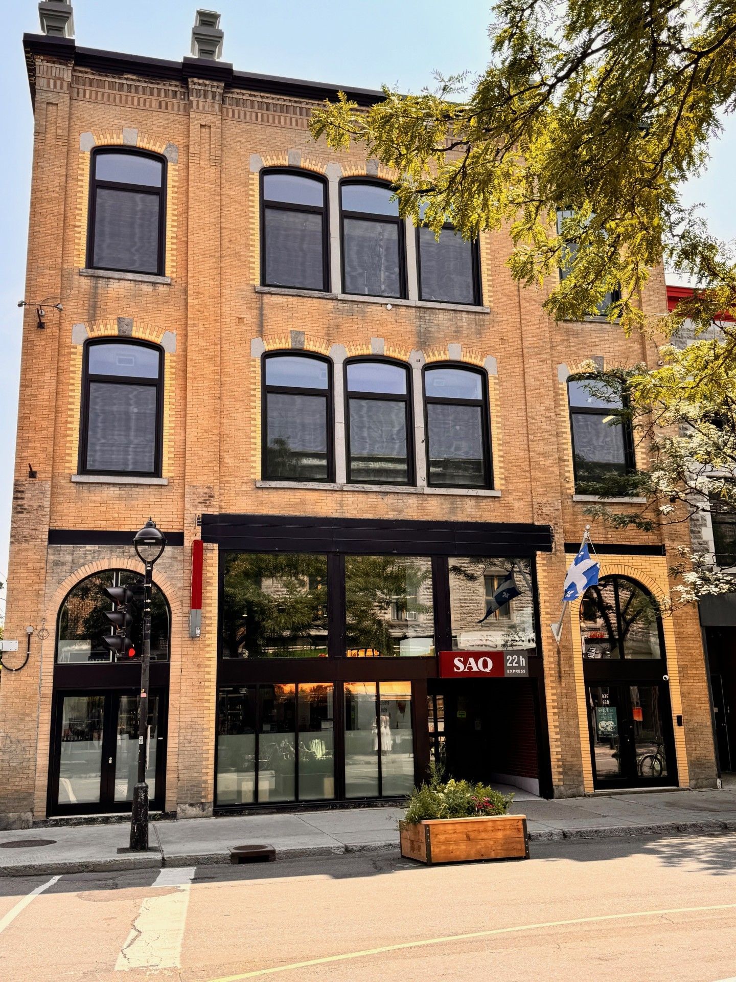 A large brick building with a lot of windows and a tree in front of it.