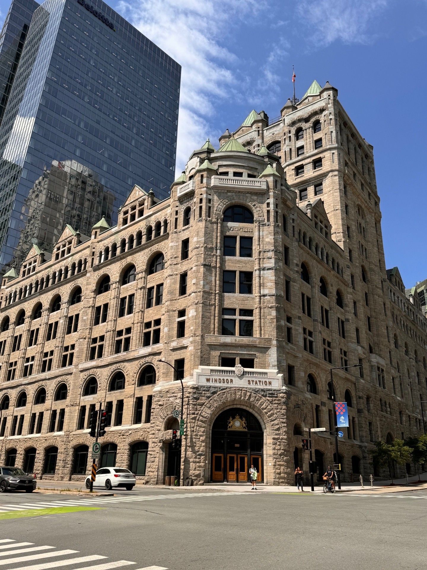 A large building with a lot of windows is sitting on the corner of a city street.