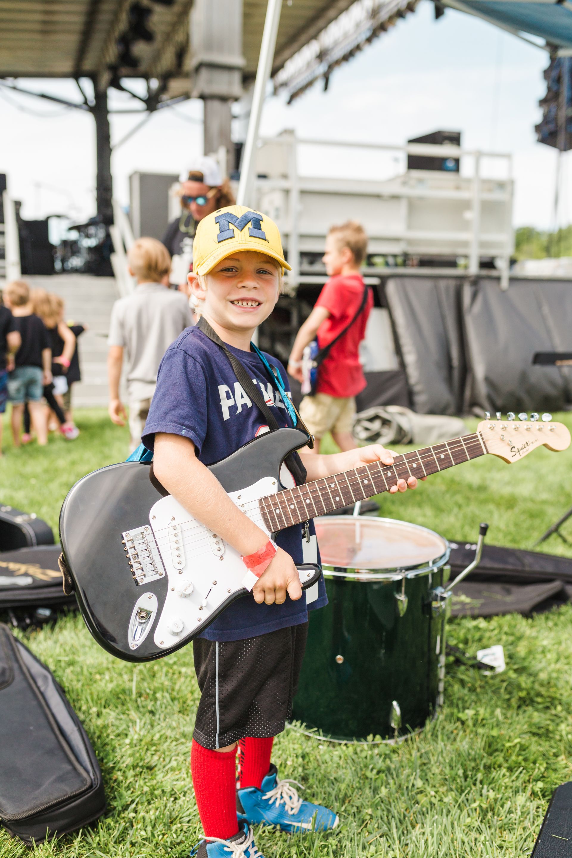 A young boy is holding a guitar in a field.