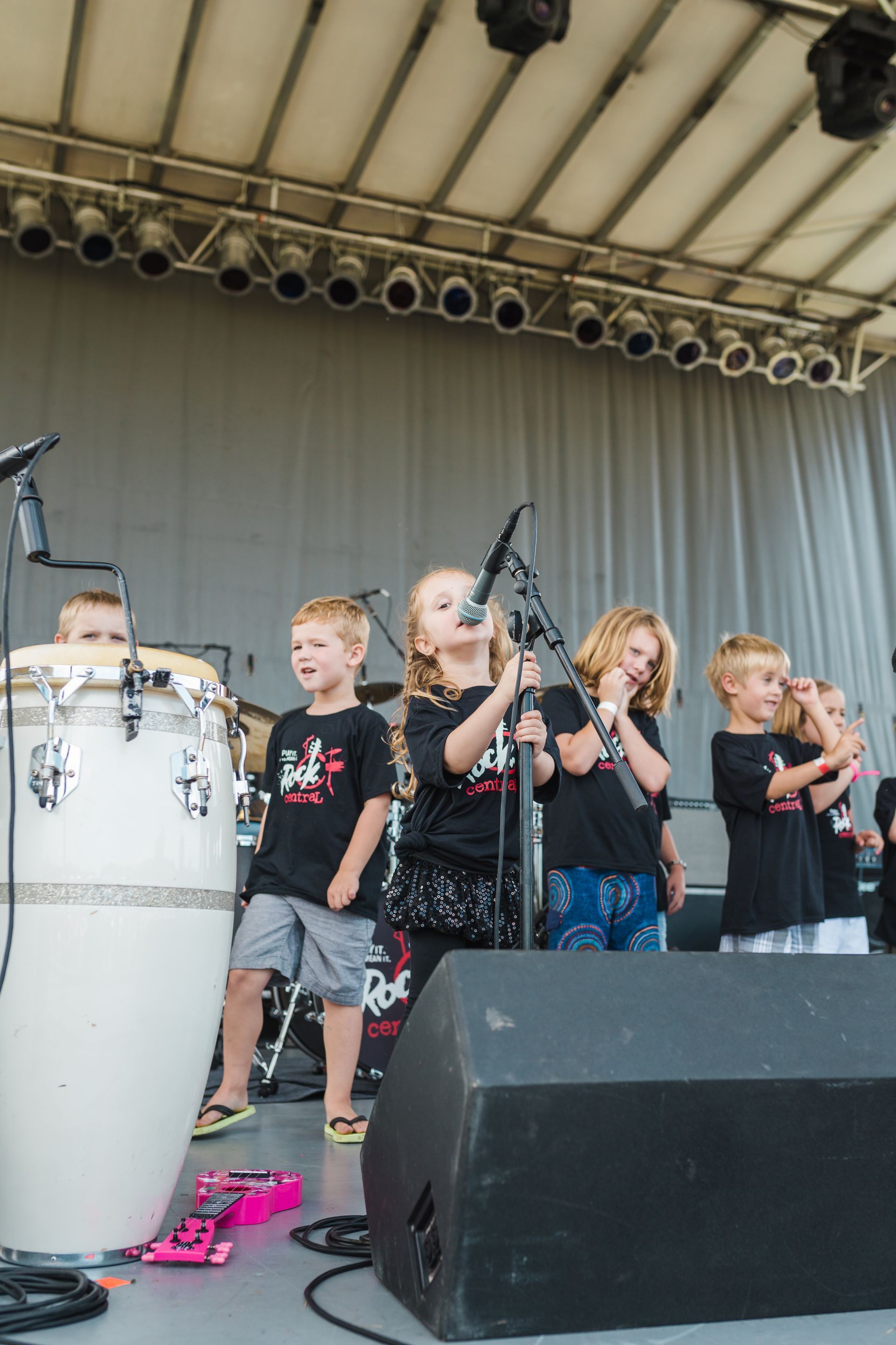 A group of young children are singing into microphones on a stage.