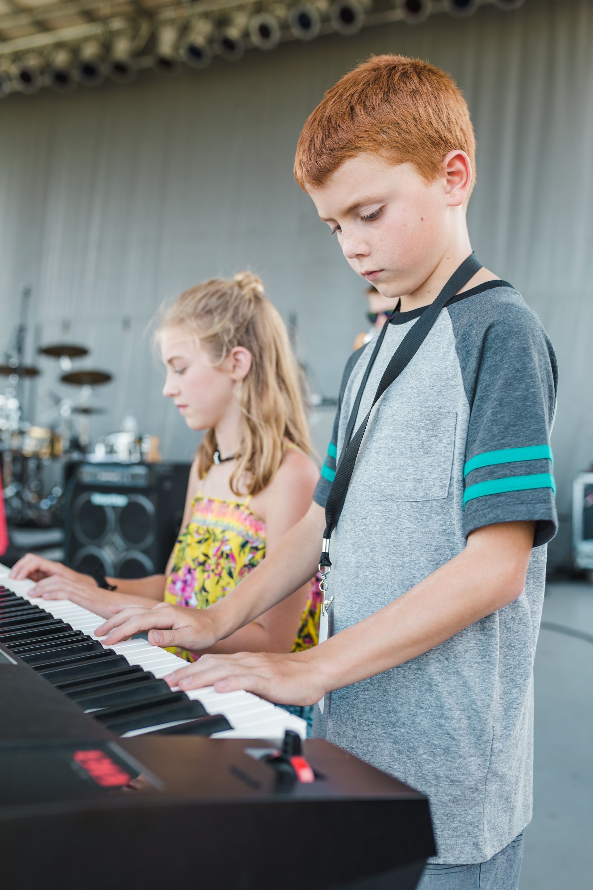A boy and a girl are playing a keyboard on a stage.