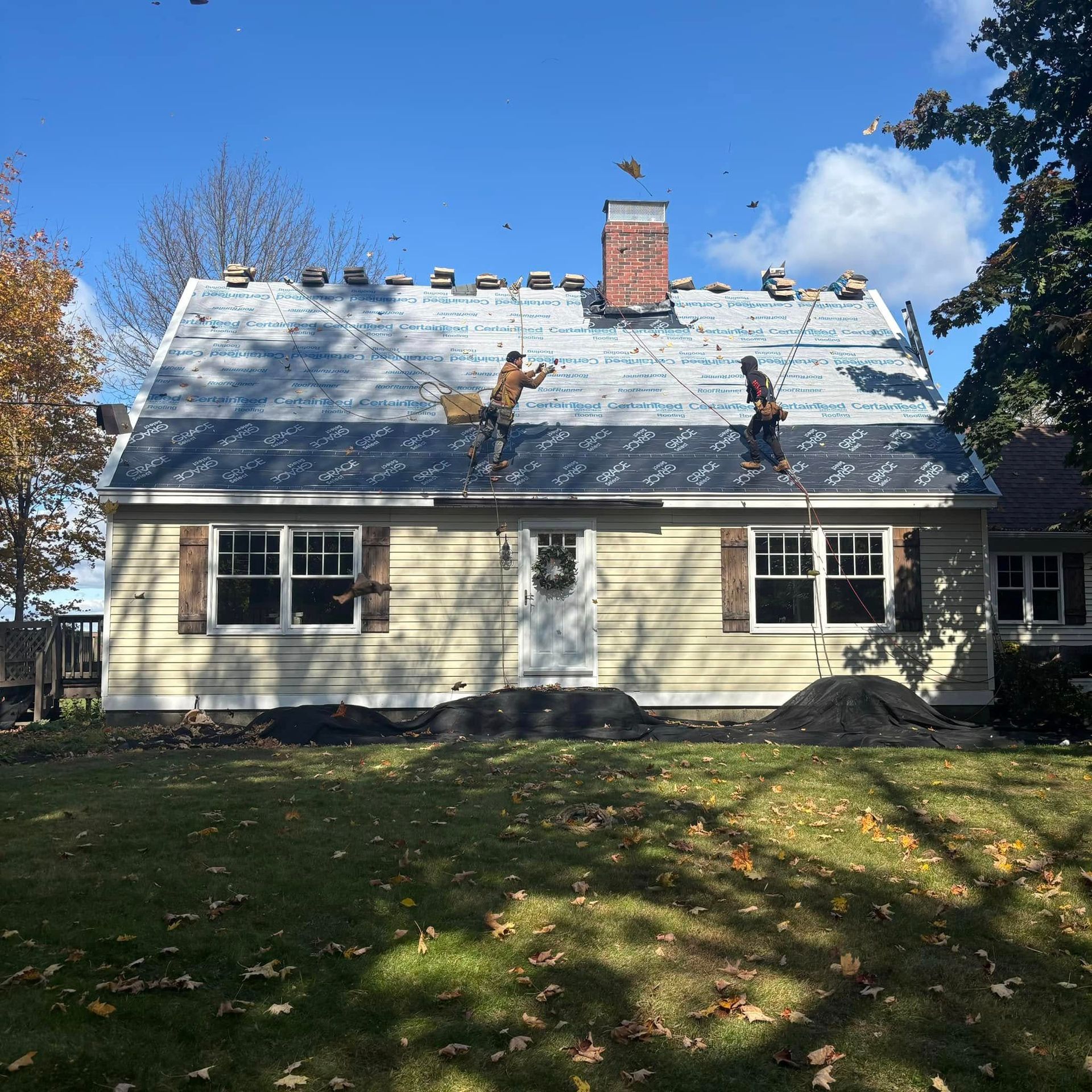 Two men are working on the roof of a house