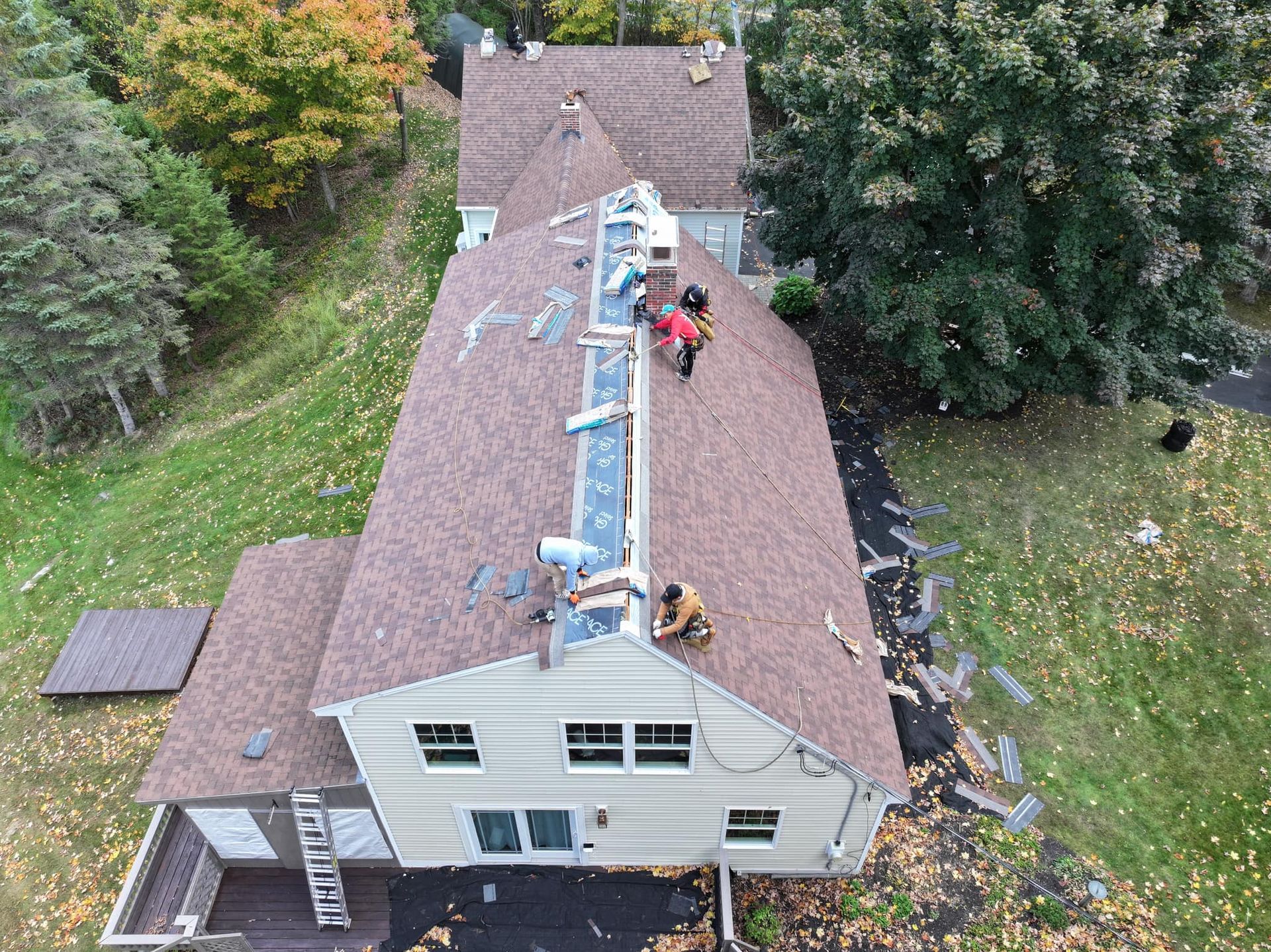 A group of people are working on the roof of a house.