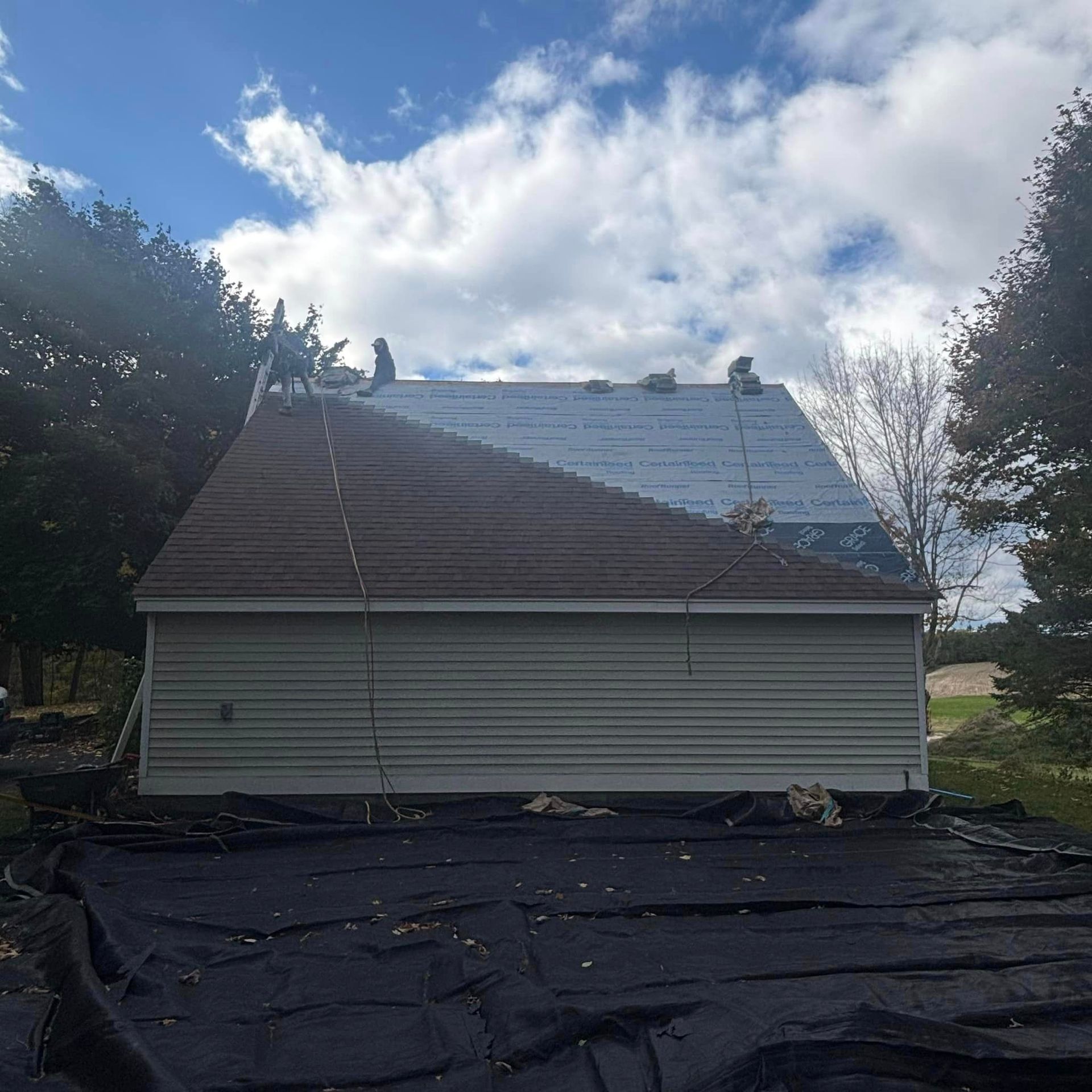A house with a roof that is being installed on a sunny day.