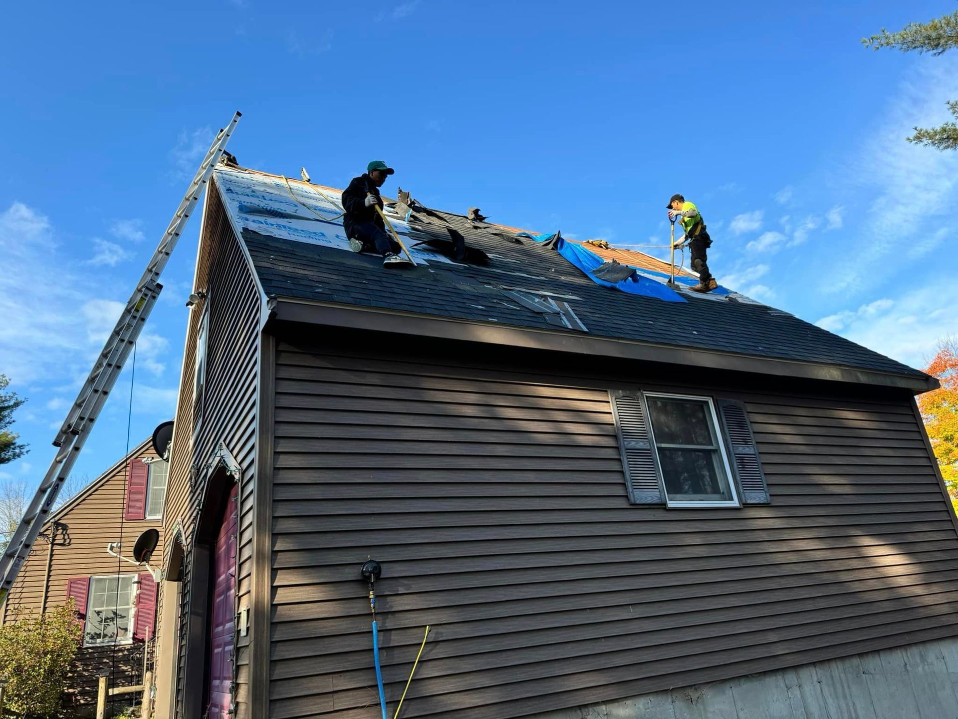 A group of men are working on the roof of a house.