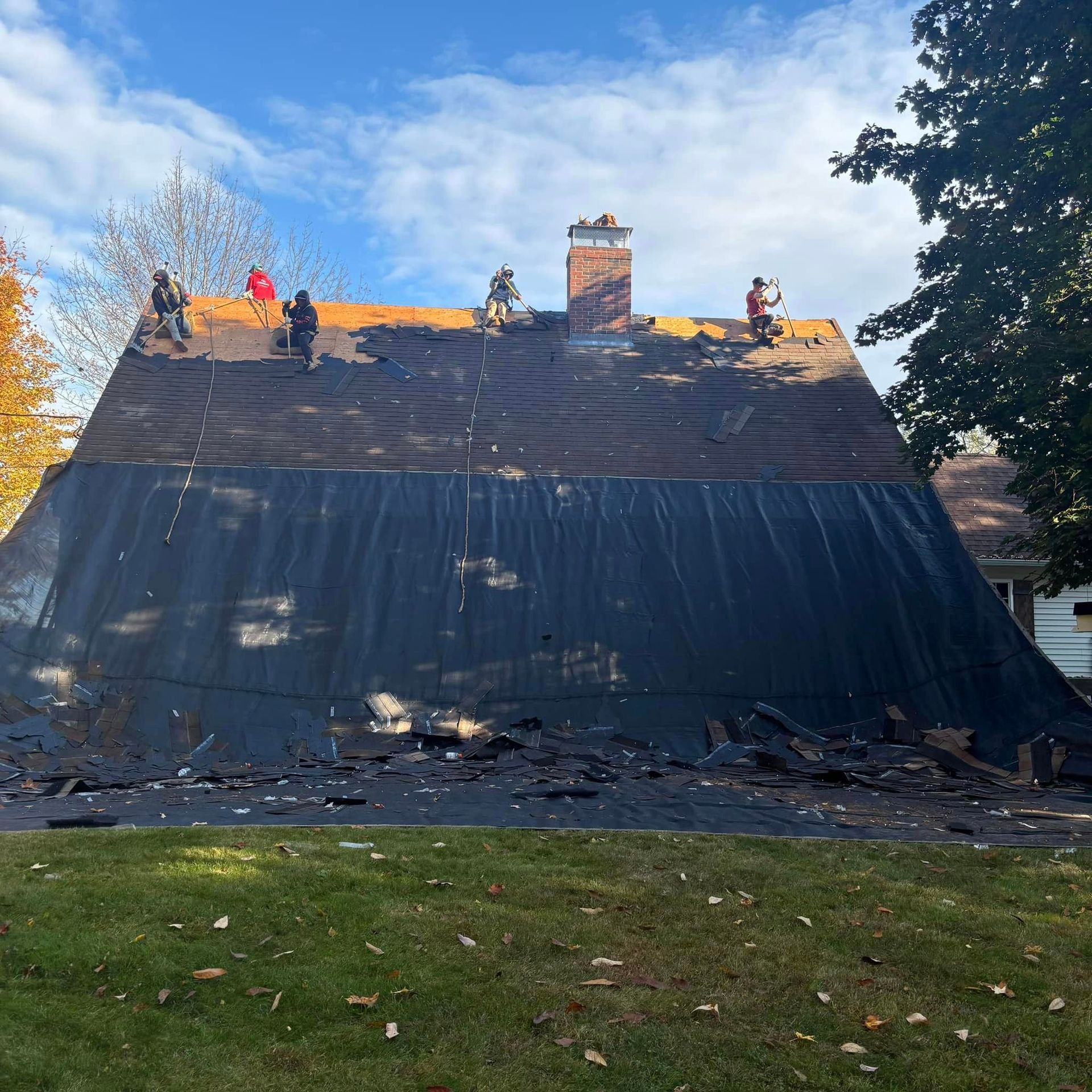 A group of people are working on the roof of a house.