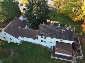 An aerial view of a large white house with a brown roof